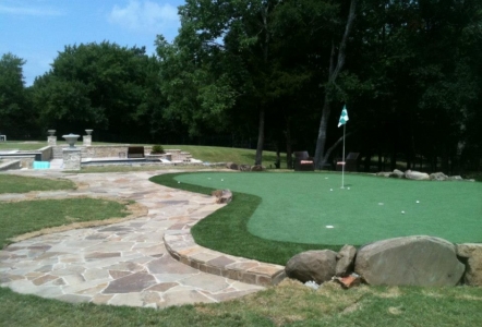 Oklahoma Flagstone pathway next to a putting green with a few Moss Boulders