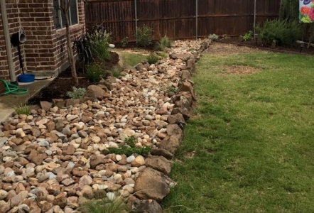 Moss Boulders were used to line the edges of a dry creek bed installed by The Patient Gardener.