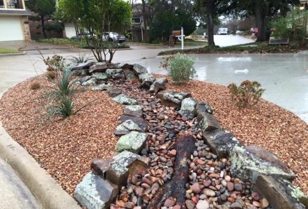 Moss Boulders used to line a dry creek bed installed by Tropical John.