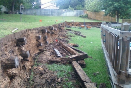 Railroad Tie retaining wall ripped out to replace with stone.